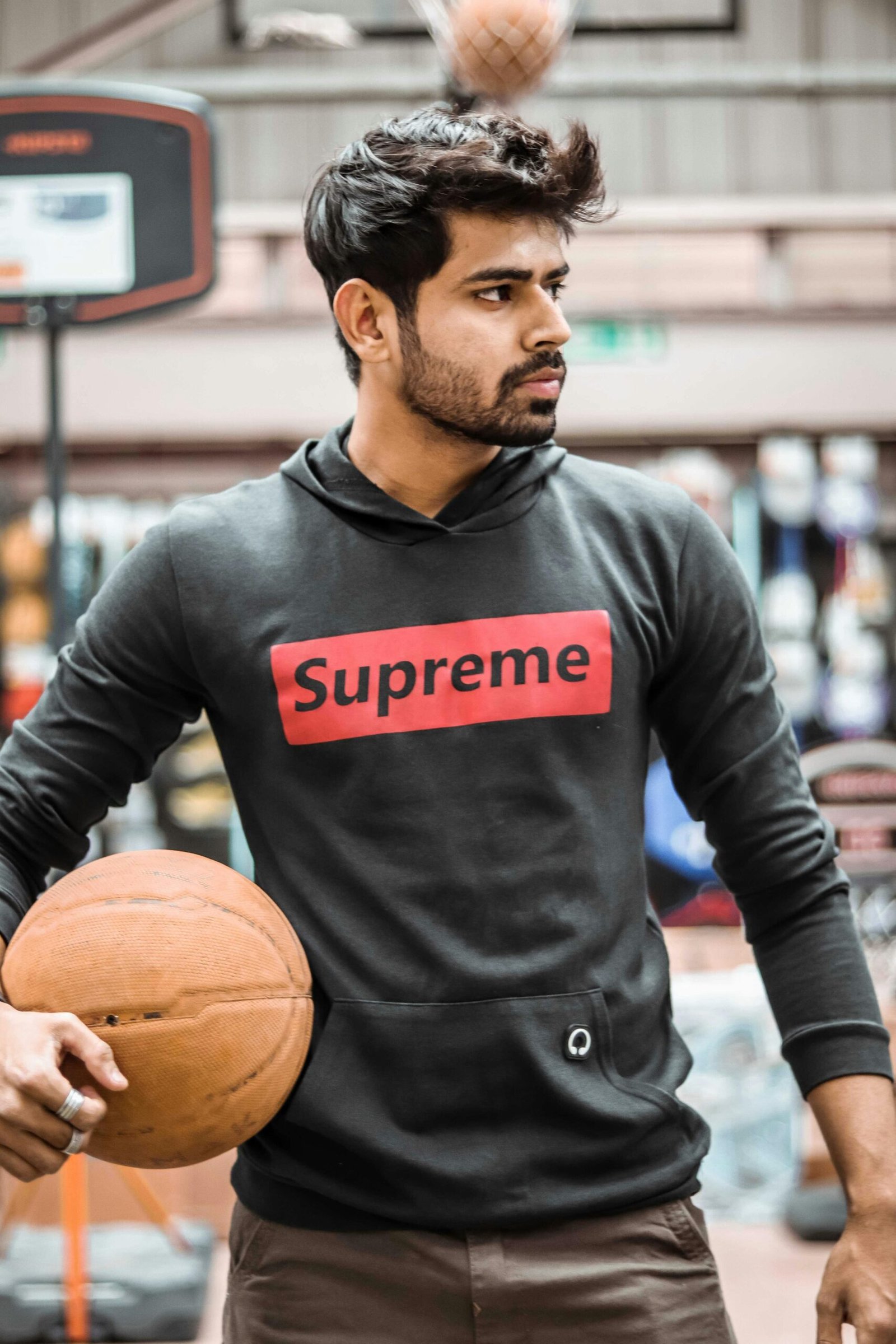 Portrait of a young man holding a basketball on an indoor court in Ahmedabad, India.